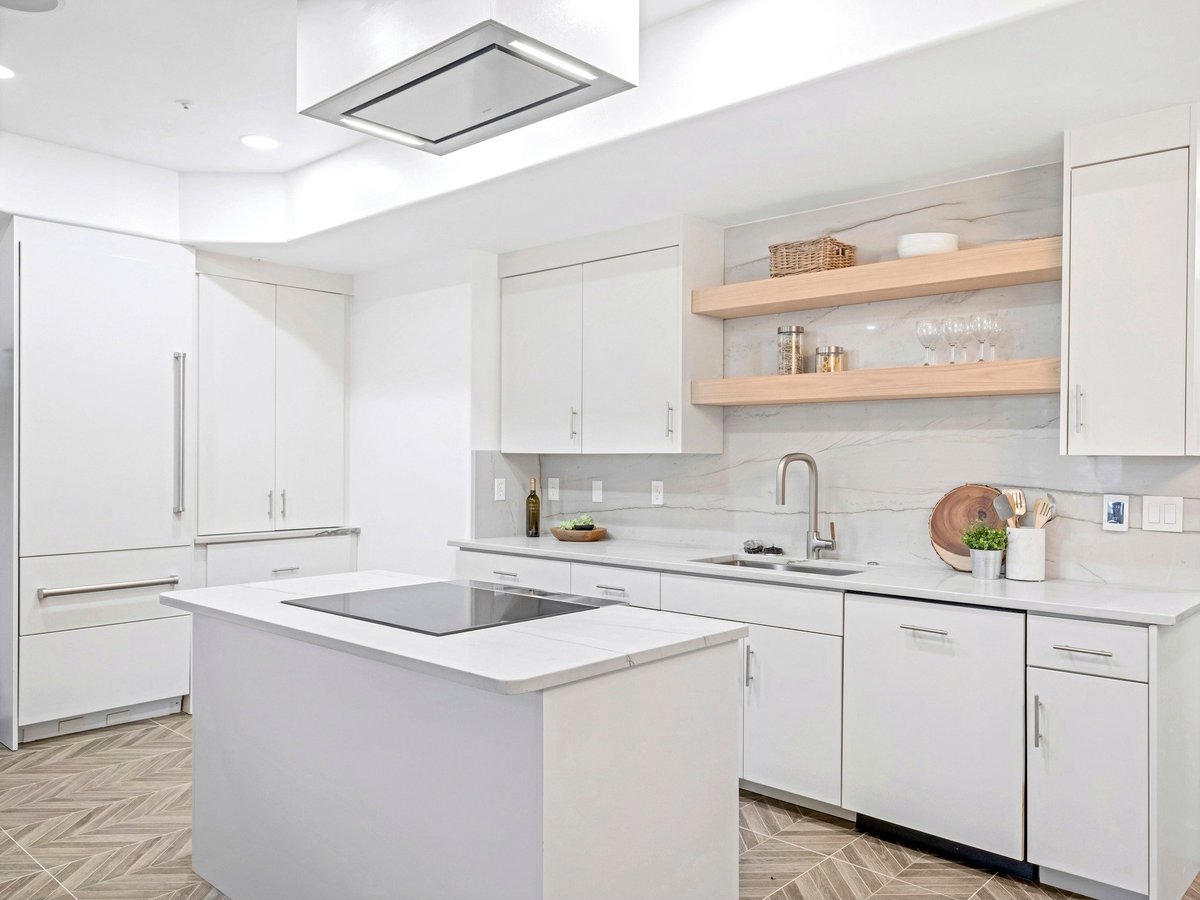 Modern white kitchen with island, stainless steel appliances, open shelving, and subway tile backsplash
