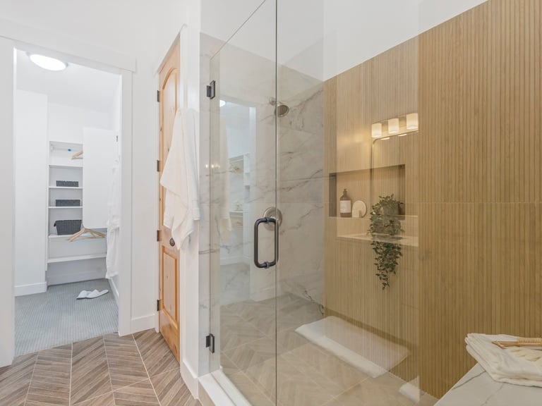 Modern bathroom with glass-enclosed shower, wood-paneled accent wall, and tiled flooring