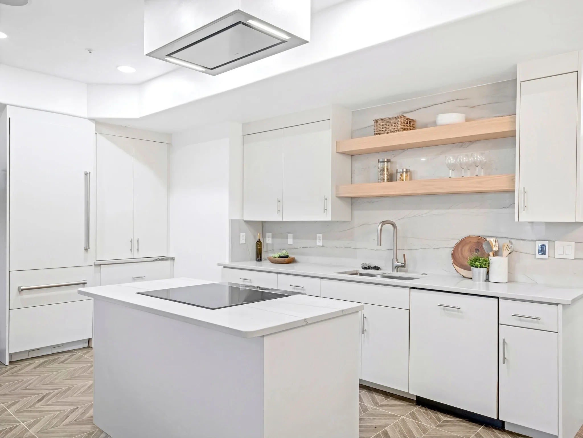 White kitchen with quartz counters, island, wood shelves, and stainless steel fixtures