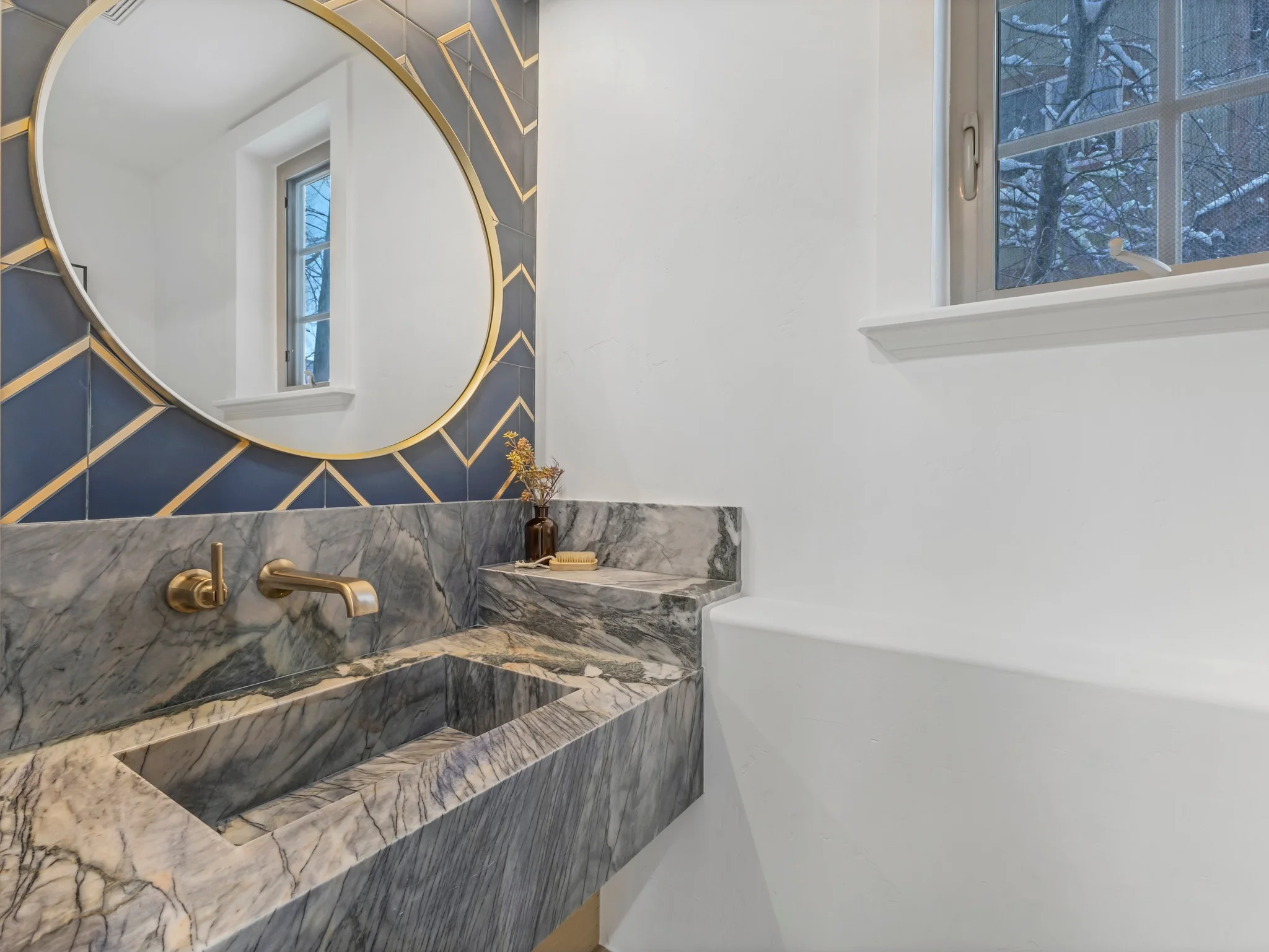 Luxury bathroom with marble vanity, gold-framed mirror, and geometric accent wall